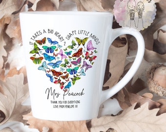 May include: White ceramic mug with a heart-shaped design made of colorful butterflies. The text "It takes a big heart to shape little minds" is printed around the heart. The mug also has the text "Mrs. Peacock" and "Thank you for everything. Love from Penelope xx".