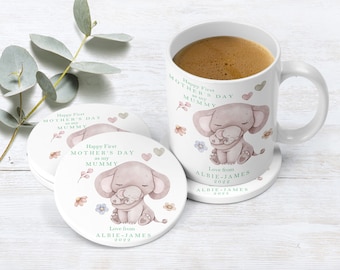 May include: White ceramic mug with a pink elephant and baby elephant illustration. The mug reads "Happy First Mother's Day as my Mummy" and "Love from Albie-James 2022". The mug is on a white coaster with the same illustration and text.