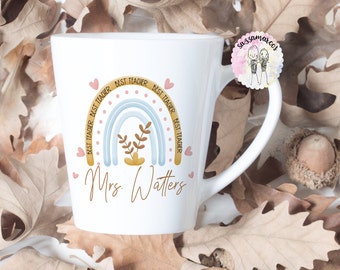 May include: White ceramic mug with a rainbow design and the text "Best Teacher" repeated around the rainbow. The mug also has the text "Mrs. Watters" in brown cursive.
