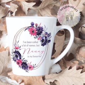 May include: White ceramic mug with a floral design and the text "I've been called a lot of names. but Nanny is my favourite!"