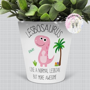 May include: White ceramic planter with a pink dinosaur illustration and the text "Lesbosaurus, like a normal lesbian but more awesome".