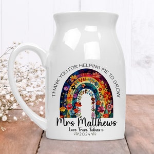 May include: White ceramic milk jug mug with a rainbow design and flowers. The text reads "Thank you for helping me to grow" and "Mrs. Matthews Love from Tobias x 2024".