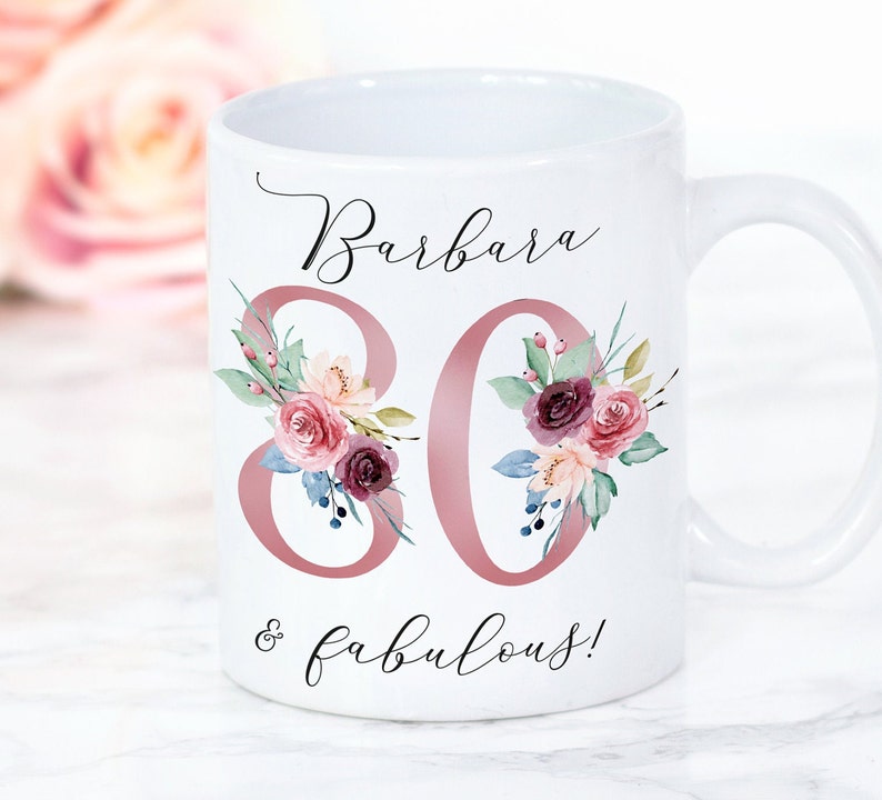 Pu&ograve; includere: Tazza in ceramica bianca con un design floreale rosa e il testo "Barbara 80 & favolosa!"