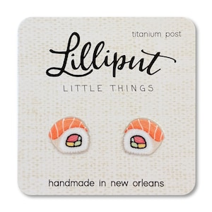 Puede incluir: Un par de pendientes de sushi con poste de titanio. Los pendientes están hechos a mano en Nueva Orleans y presentan un pequeño diseño detallado de un rollo de sushi.