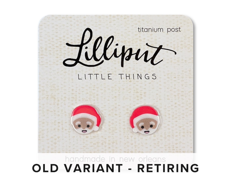 May include: A pair of Santa Claus earrings with red hats and white trim. The earrings are made of acrylic and have a titanium post. The card reads "Lilliput Little Things" and "Old Variant - Retiring".