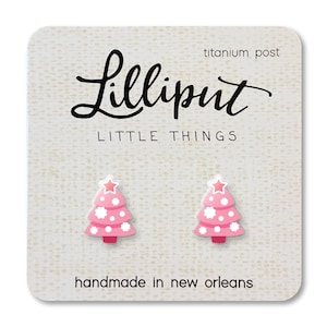 May include: Pink Christmas tree earrings with white polka dots and a star, presented on a white card. The card features the text "Lilliput LITTLE THINGS" and "handmade in new orleans". The earrings have titanium posts.