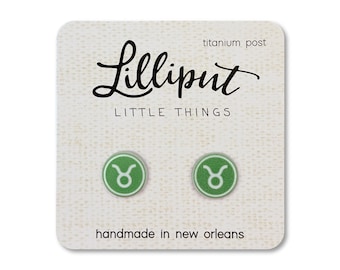 Op de afbeelding: Groene stier-sterrenbeeld oorbellen met titanium pinnen. De oorbellen zijn handgemaakt in New Orleans en worden verpakt op een kaart met de tekst "Lilliput Little Things" en "handmade in new orleans".