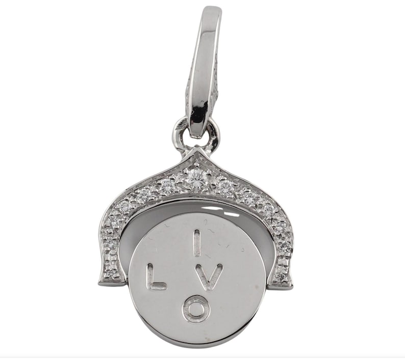 May include: A silver charm with a spinning circle that reads 'I LOVE' on it. The charm is decorated with small, clear stones around the edge.