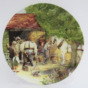 Può includere: Piatto decorativo con una scena rurale di un fabbro che ferra un cavallo. Il piatto raffigura un fienile, cavalli e persone in un'illustrazione dettagliata e colorata. Sono presenti anche un albero e vari animali.