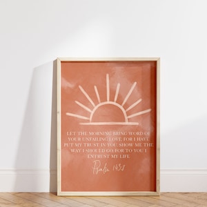 Puede incluir: Una impresión de arte digital con una ilustración de amanecer y una cita del Salmo 143:8. El fondo es de color naranja terracota y el texto es blanco. La cita dice: "Que la mañana traiga la palabra de tu amor inquebrantable, porque he puesto mi confianza en ti. Muéstrame el camino que debo seguir, porque a ti confío mi vida."