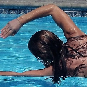 Puede incluir: Una mujer con un traje de ba&ntilde;o negro est&aacute; nadando en una piscina. Est&aacute; haciendo un ejercicio de espalda con el brazo extendido por encima del agua.