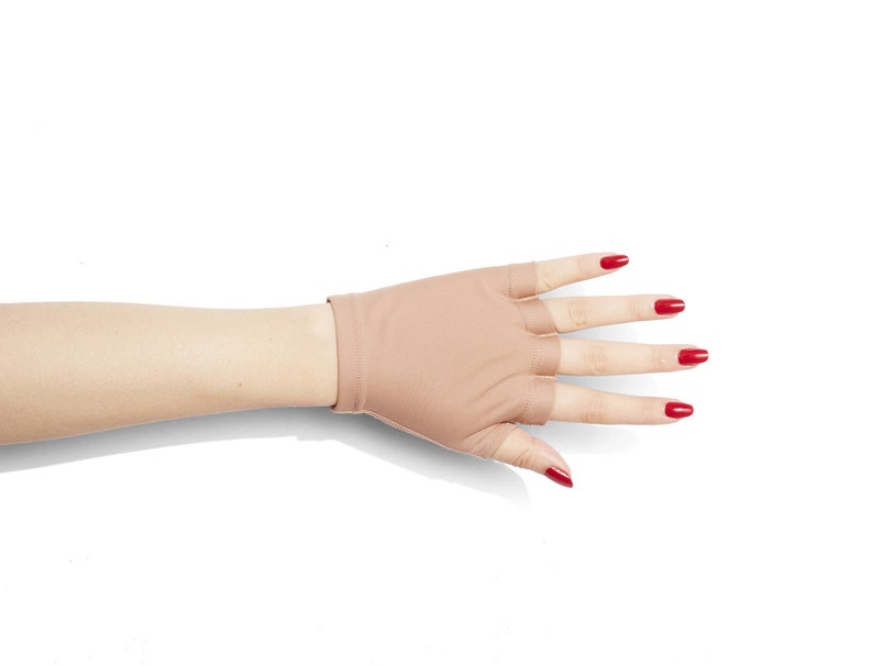 Puede incluir: Un par de guantes sin dedos de color carne con un primer plano de la mano que lleva los guantes. Las u&ntilde;as est&aacute;n pintadas de rojo brillante.
