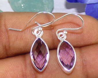 May include: A pair of silver earrings with purple amethyst stones. The stones are marquise shaped and have a faceted cut. The earrings have a simple hook fastening.