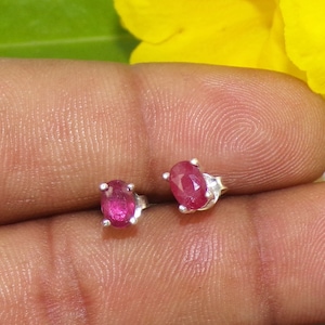 Pode incluir: Um par de brincos de prata com pedras de rubi rosa ovaladas.