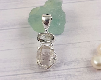May include: A silver pendant featuring a clear, faceted quartz crystal with a smaller, rectangular quartz crystal above it.