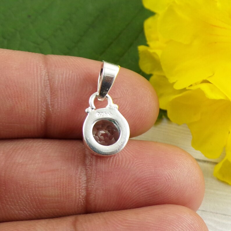 May include: Silver pendant with a round clear stone set in a bezel setting. The back of the pendant has a silver bail and the inscription "925".