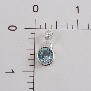 May include: A silver pendant with a light blue oval gemstone. The pendant is about 1 inch long.