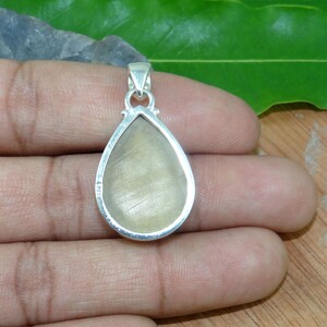 May include: Silver pendant with a teardrop-shaped, translucent, light brown gemstone. The pendant is set in a silver bezel and has a bail for attaching a chain.
