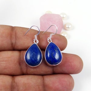 May include: A pair of silver teardrop earrings with blue lapis lazuli gemstones.