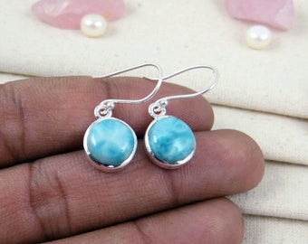 May include: A pair of silver dangle earrings with round blue and white gemstone drops.