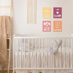 May include: Four framed prints with positive affirmations for children. The prints are in a nursery setting with a white cot and a brown blanket on a ladder.