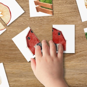 May include: A set of colorful cards with images of a red barn, a green vegetable garden, a cup of hot chocolate, and a sliced apple. The cards are on a wooden surface.