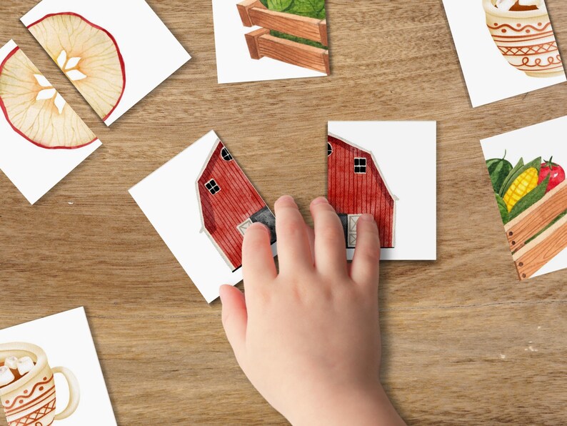 May include: A set of colorful cards with images of a red barn, a green vegetable garden, a cup of hot chocolate, and a sliced apple. The cards are on a wooden surface.