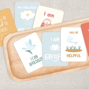 May include: A set of colourful affirmation cards with illustrations and positive messages. The cards include phrases like "I will be kind to others", "I am grateful", and "I will say thank you".