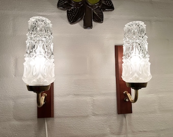 Könnte beinhalten: Zwei vintage Wandleuchten mit mattierten Glasschirmen und Messingakzenten. Die Leuchten sind an Holzplatten an der Wand montiert.