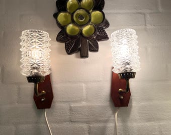 Könnte beinhalten: Zwei vintage Wandleuchten mit klaren Glasschirmen und Messingakzenten. Die Schirme haben ein Diamantenmuster und sind mit Glühbirnen beleuchtet. Die Leuchten sind an Holzplatten an der Wand montiert.
