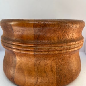 Puede incluir: Un tazón de madera grande y redondo con un acabado marrón natural. El tazón tiene un borde ligeramente acampanado y una superficie lisa y pulida.