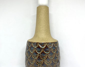 May include: A ceramic table lamp with a brown and blue patterned base. The base has a textured, scaly design. The lamp has a white shade.