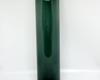 May include: A tall, cylindrical vase in a deep teal color. The vase has a smooth, glossy finish and a slightly darker base. The design is simple and modern, suitable for displaying flowers or as a decorative accent piece. The vase is approximately 12 inches tall.