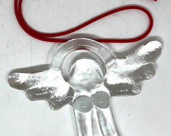May include: A clear glass angel ornament featuring a halo and outstretched wings. The figure has a smooth, translucent finish and is attached to a thin, bright red cord for hanging, designed for decorative display purposes.
