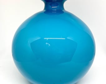 May include: A large, round, turquoise blue glass vase with a wide mouth.
