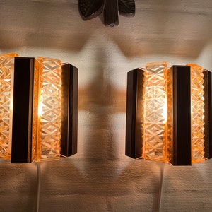 May include: Two wall-mounted light fixtures with geometric glass panels and a copper finish. The lights are turned on and illuminate the room.
