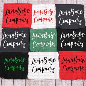 May include: Nine different t-shirts with the text "LunaBabe Company" printed on them. The shirts are in various colors, including red, white, black, and green.
