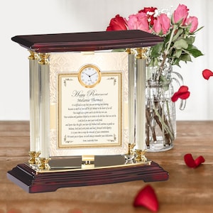 May include: A mahogany wood clock with gold accents and a glass front. The clock face is white with black numbers and hands. The clock is on a wooden table with red rose petals scattered around it. The glass front has a plaque with the text "Happy Retirement Melanie Thomas" and a poem about retirement.