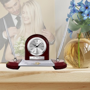 May include: A mahogany desk clock with silver face and hands, two silver pens, and a silver plaque with the text "Tim L. Walker, RN 20 years of service at St. Vincent's Hospital".