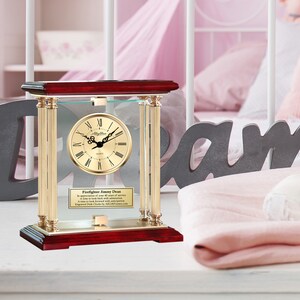 May include: A gold and mahogany clock with a glass front and a personalized inscription for a firefighter. The inscription reads "Firefighter Jimmy Dean In appreciation of your 30 years of service a time to look back with admiration and a time to look forward with anticipation. A time to cherish the memories. Engraved Desk Clock Crafted with Precision."