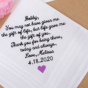 May include: White handkerchief with black embroidered text that reads "Bobby, You may not have given me the gift of life, but life gave me the gift of you. Thank you for being there, today and always. Love, Melissa 4.18.2020". A small purple heart is embroidered in the bottom right corner.