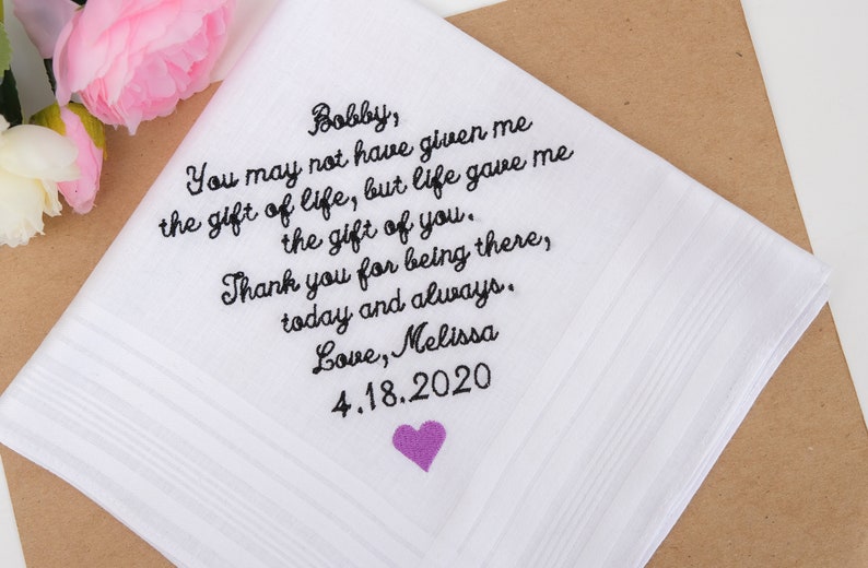 May include: White handkerchief with black embroidered text that reads "Bobby, You may not have given me the gift of life, but life gave me the gift of you. Thank you for being there, today and always. Love, Melissa 4.18.2020". A small purple heart is embroidered in the bottom right corner.