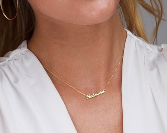 May include: A gold chain necklace with a delicate nameplate pendant that reads "Natasha".