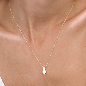 Peut inclure: Un collier en or délicat avec un petit pendentif en forme de chat. Le pendentif est une silhouette simple d'un chat. Le collier est porté par une personne portant un débardeur blanc. La chaîne est fine.