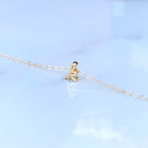 May include: A delicate gold chain necklace with a small, cursive letter 'K' pendant.