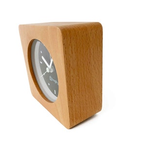 Peut inclure: Une horloge en bois avec un cadran noir et des aiguilles blanches. L'horloge est dans un cadre carr&eacute; aux coins arrondis. Le cadran de l'horloge porte l'inscription "bogbaby".
