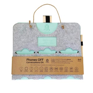 Op de afbeelding: Grijze vilten hangende telefoonhouder met een lichtblauw interieur en wolk-vormige uitsparingen. Voorzien van een houten handvat en de tekst "Phones OFF Conversations ON." Inclusief een vak voor tablets en 6+1 vakken.