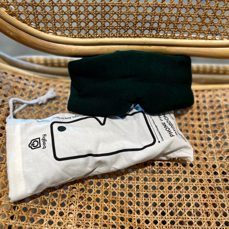 May include: A dark green sleep mask with a white pouch that says "Phone Free Zone" and has a phone outline with the text "Designed to keep you comfy" and a logo that says "Poggy".