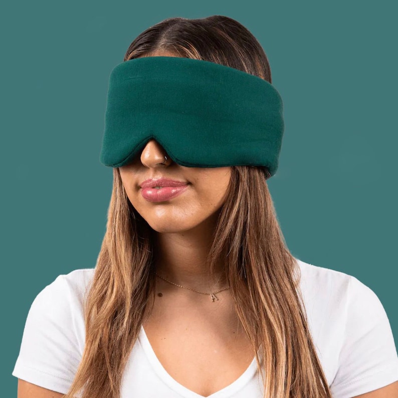 May include: A dark green sleep mask made of soft fabric. The mask covers the eyes and is designed to block out light.