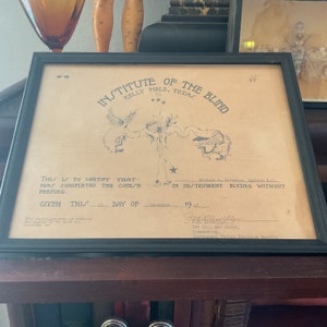 May include: A framed certificate from the Institute of the Blind at Kelly Field, Texas, dated 15 December 1912. The certificate states that the recipient has completed the course in instrument flying without peeping. The certificate is signed by Michael L. Grinnina, Captain A.C., and J.M. Lineberry, 1st Lt., Air Corps, Commanding, Instrument Flying Training Section.